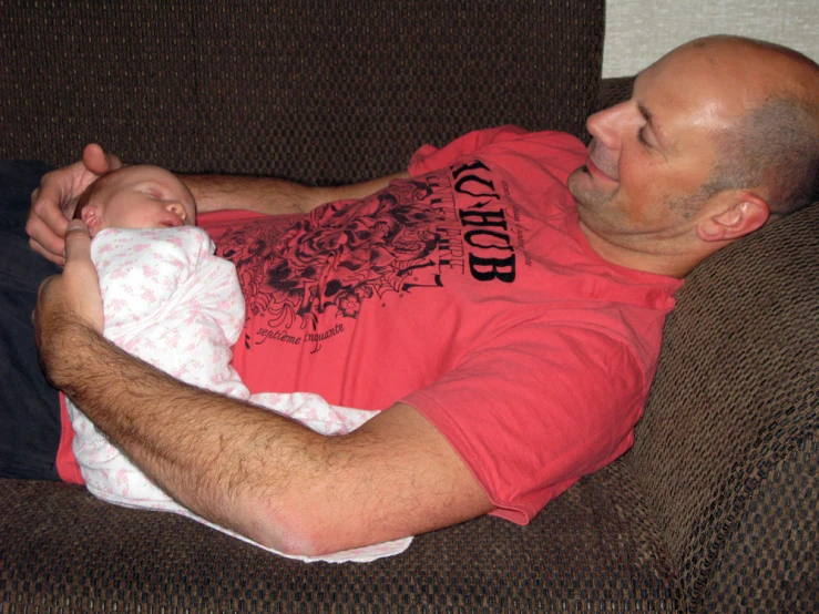 a man holding a baby in his lap on a sofa