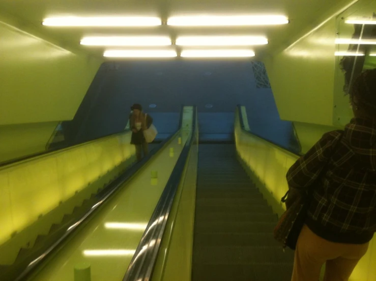 people riding down an escalator during the day