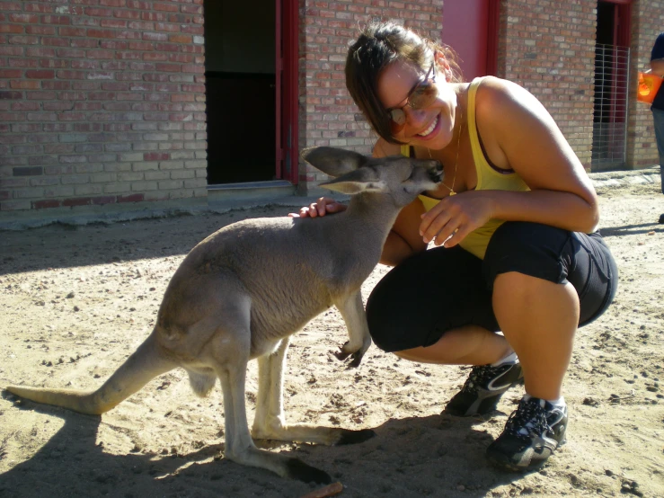 the woman is holding onto the kangaroo by its tail