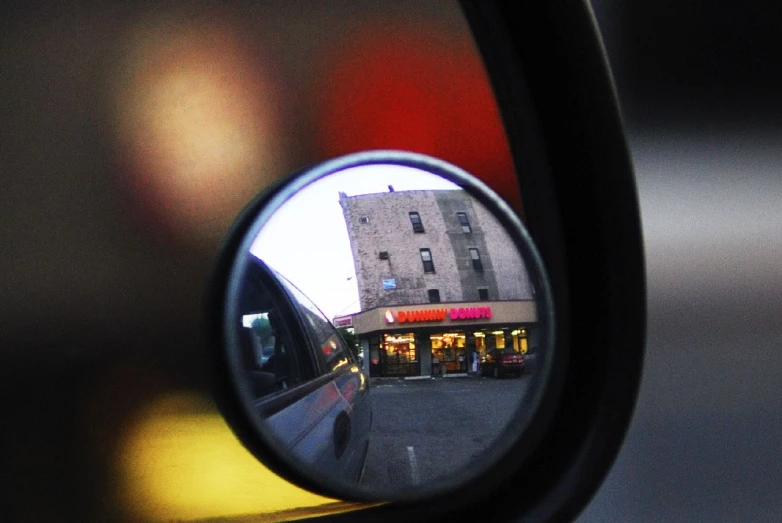 a rear view mirror is showing a store in the side mirror