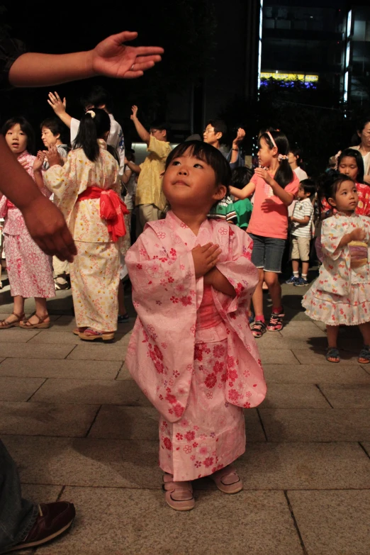 a child dressed in pink dress with a lot of people standing around