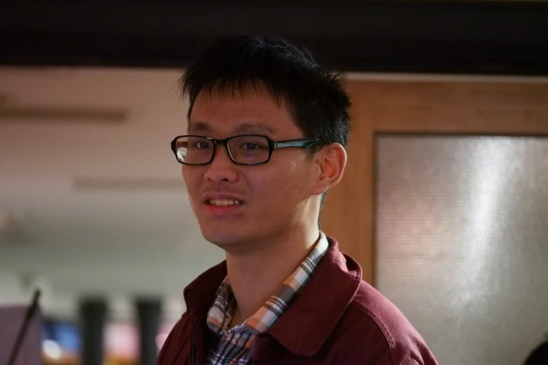 a man in red shirt and glasses standing next to a door