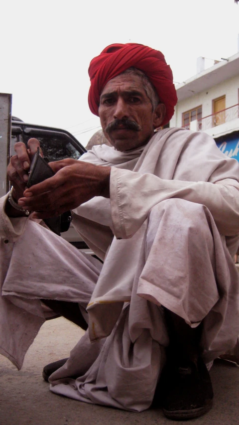 man wearing red turban sitting with other men around him