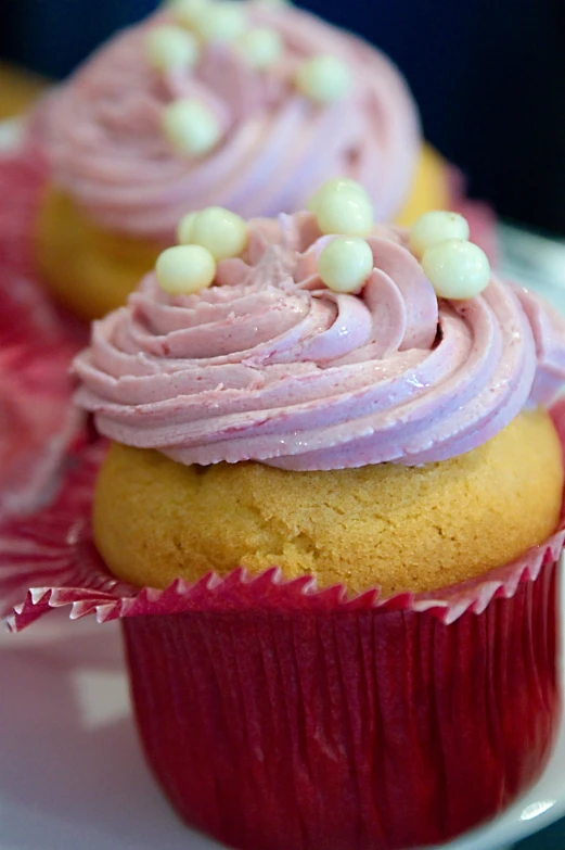 pink frosted cupcakes sit on the plate