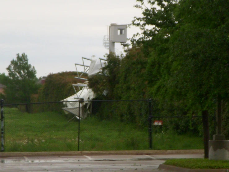 a po taken through a fence shows the old equipment left on a grassy field