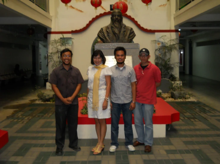 a group of young adults posing in front of a statue