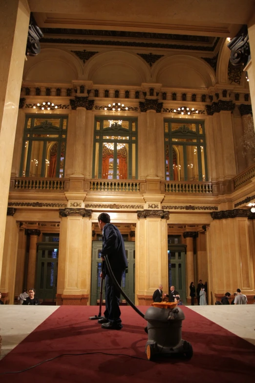 a man with a vacuum and a duster is sweeping up a large building