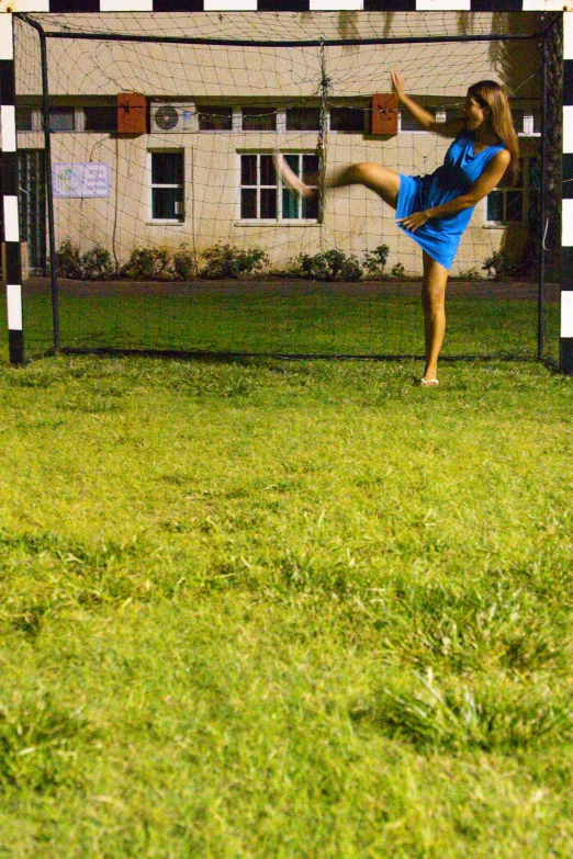 a woman kicking a soccer ball across a grass field