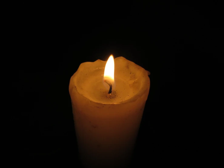 a lit candle on a black surface