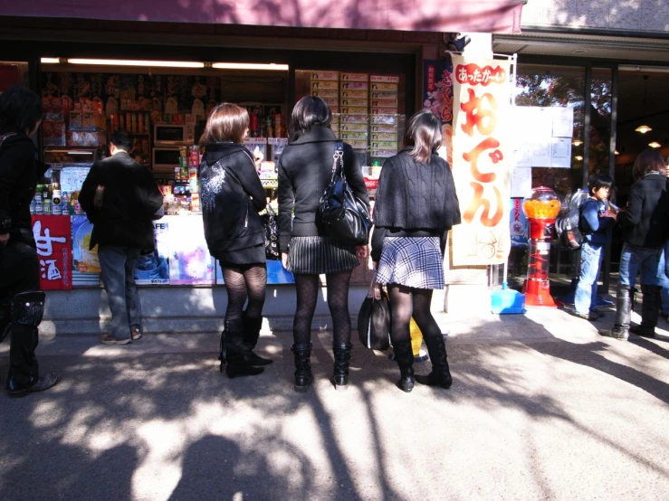 three women with their backs turned are standing in front of a store