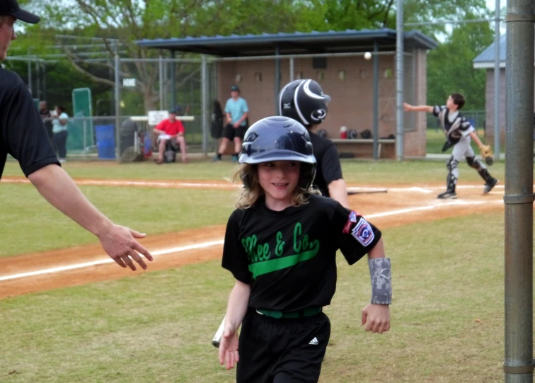 a girl walking up to first base during a little league game