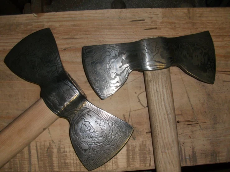 two large metal axes sitting on a wooden surface