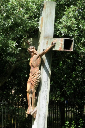 an old and dirty wooden crucifix with leaves on it