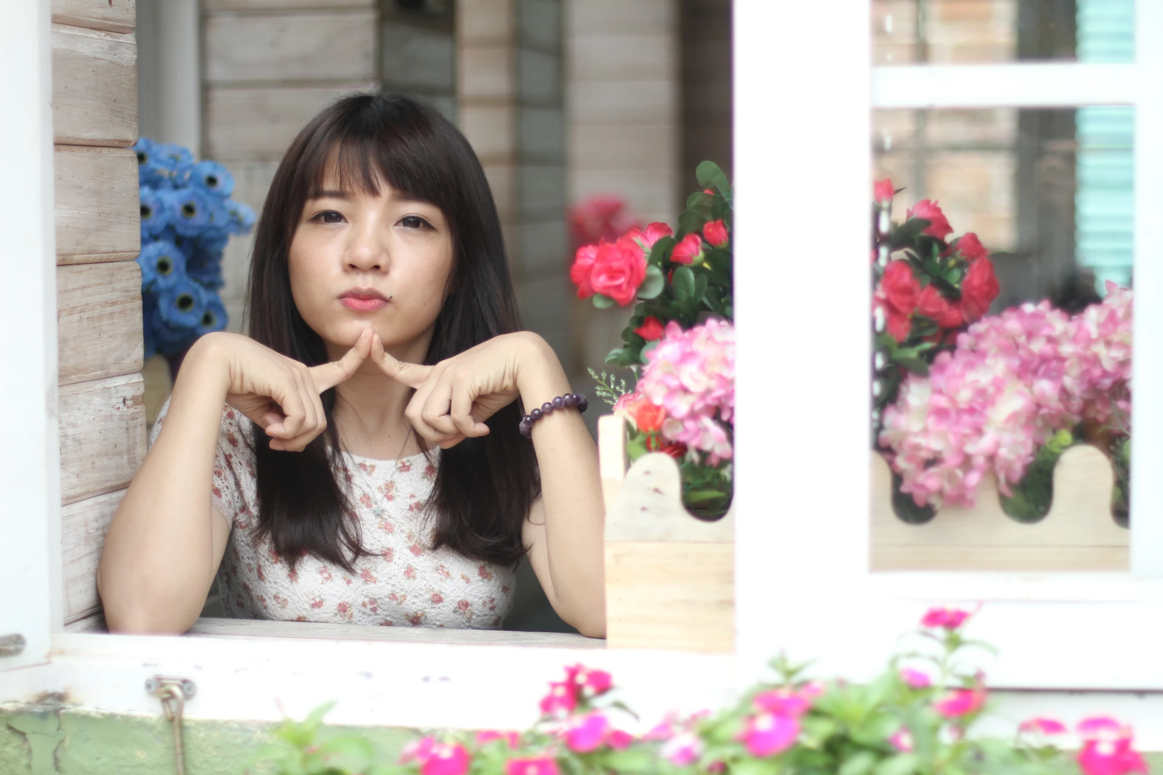 an asian lady holding out her hands looking out the window