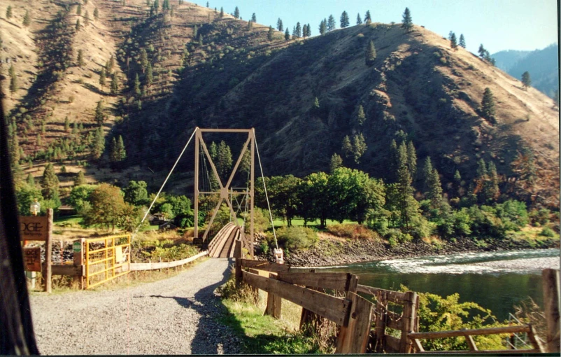 a view of the mountains and a wooden bridge over a river