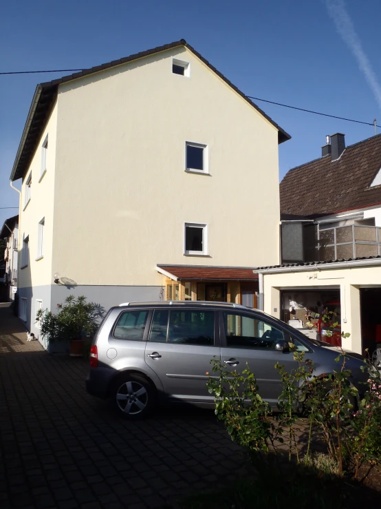 the silver car is parked in front of the house