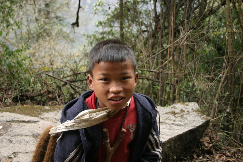 a boy wearing a scarf is walking in the forest