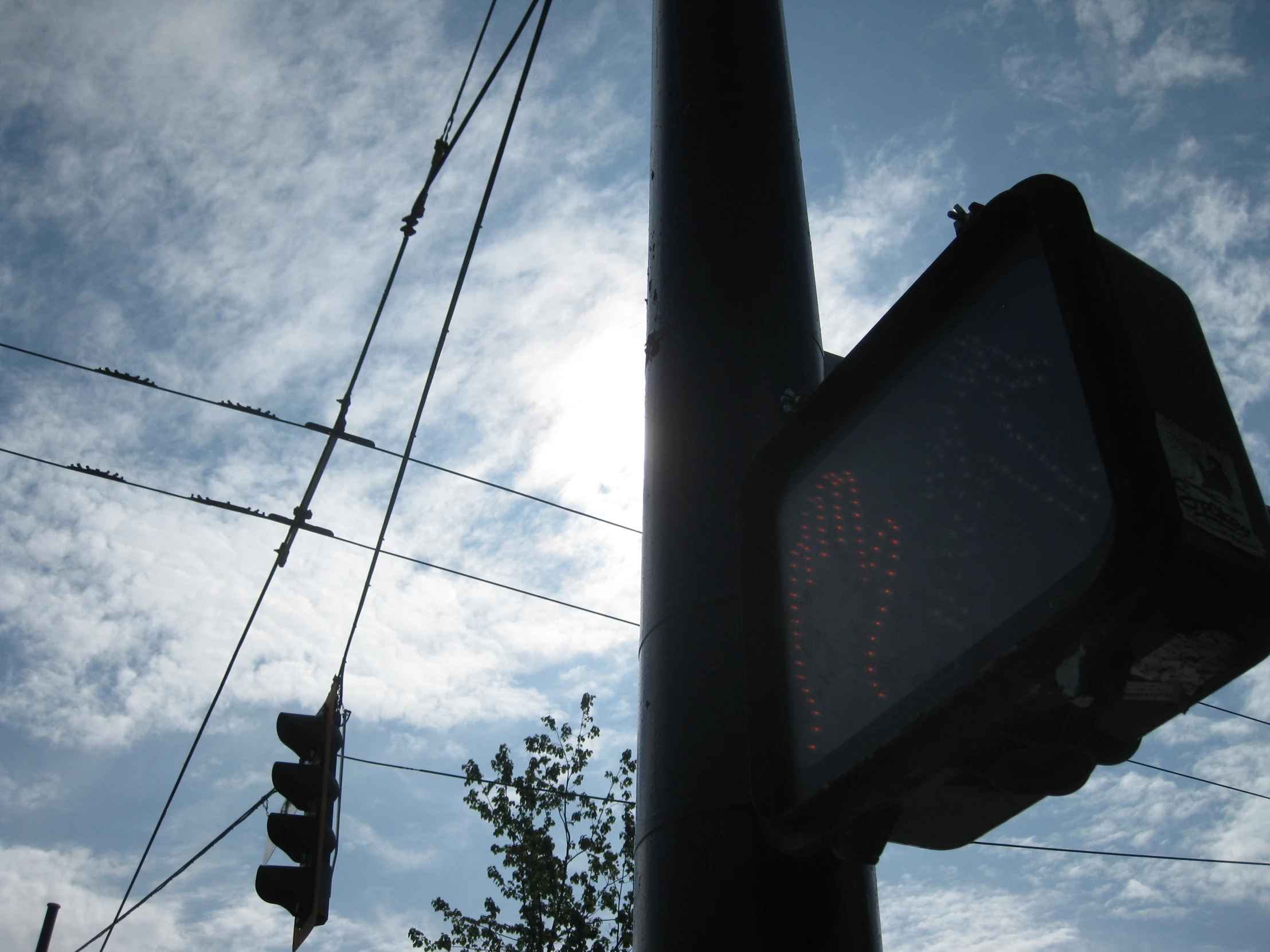 the stop light is below the wires on a pole