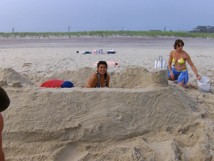 two women sitting in the sand on a beach