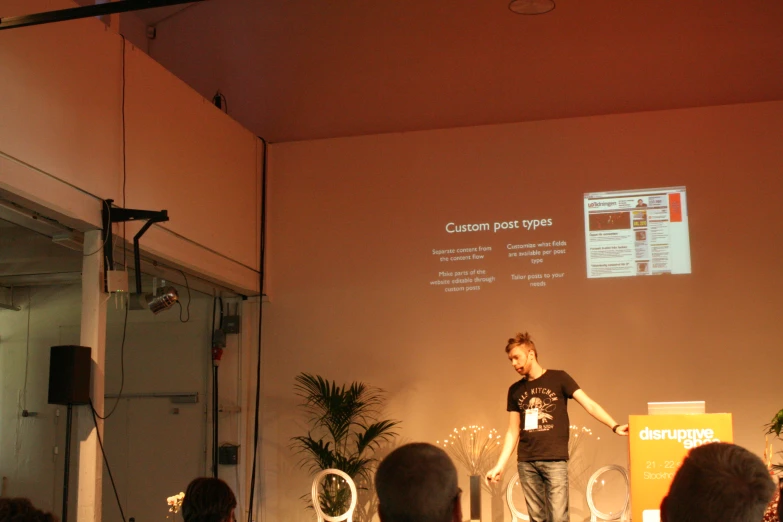 a man in black shirt standing in front of a projection screen