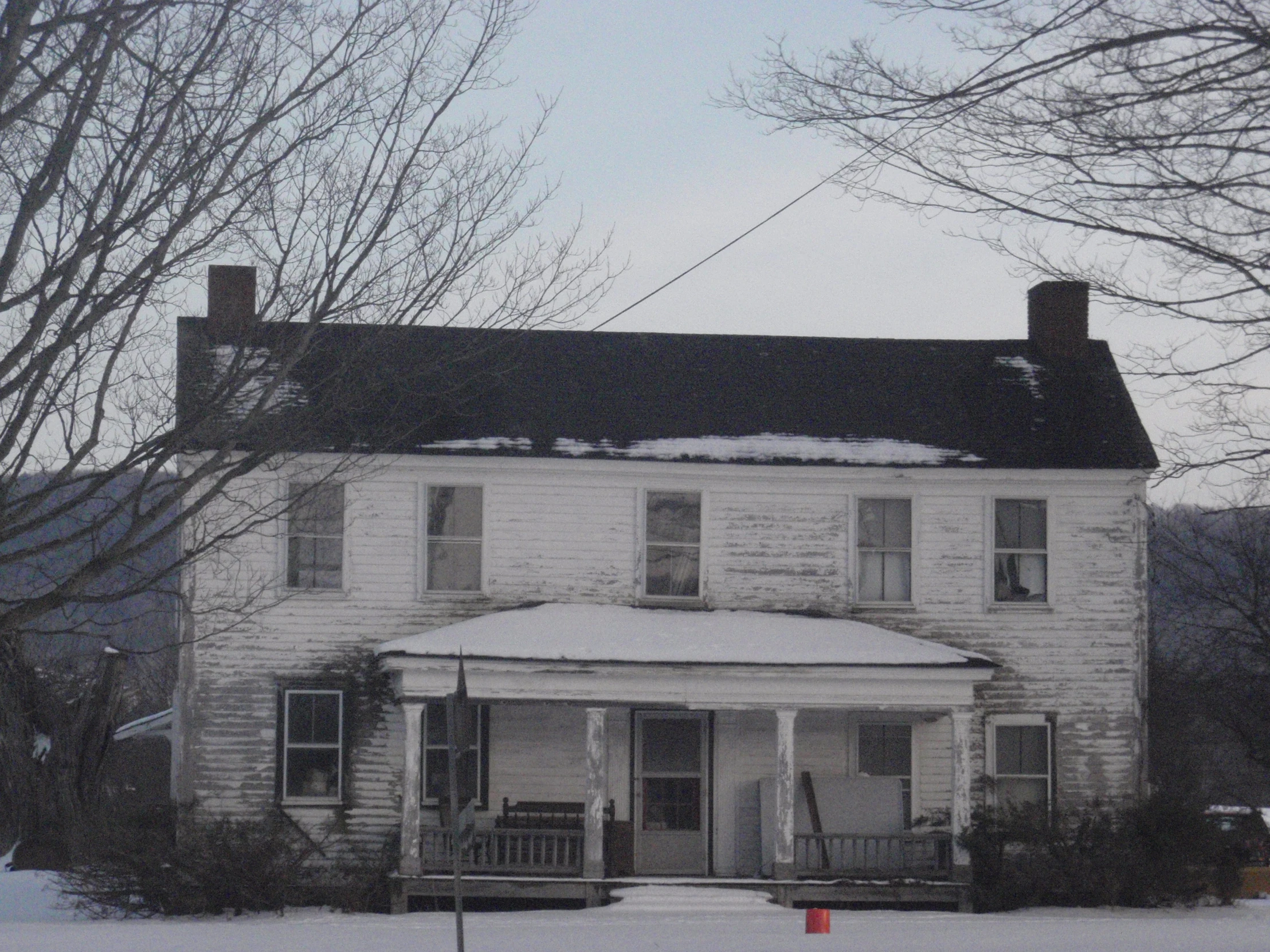 an old house that has snow on the roof and windows