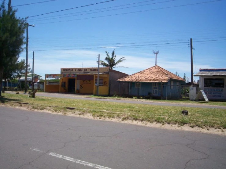 small yellow buildings sit behind the grass by a road