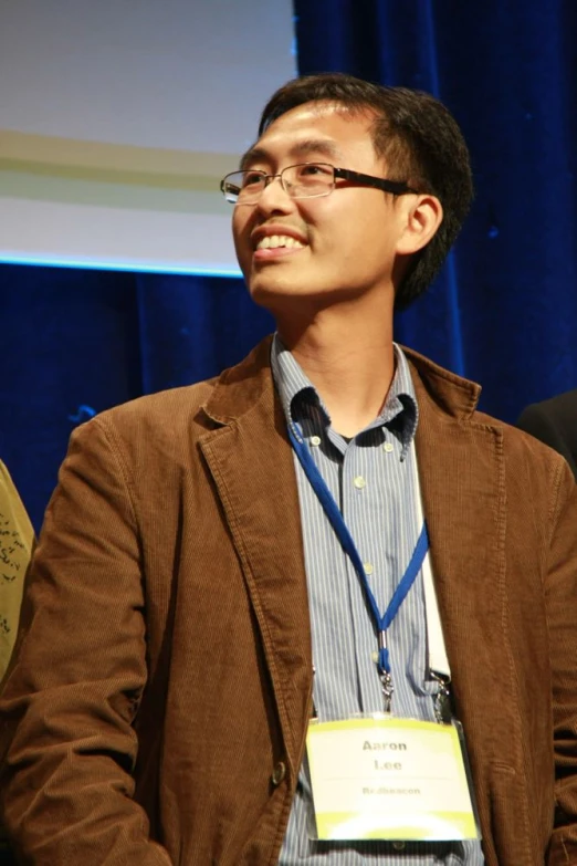 a man smiling and talking to someone in a auditorium