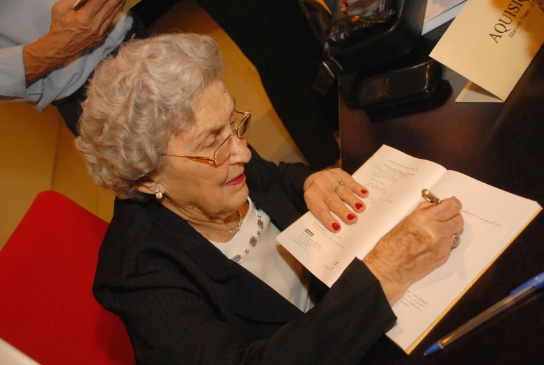 a woman sitting at a table reading a book