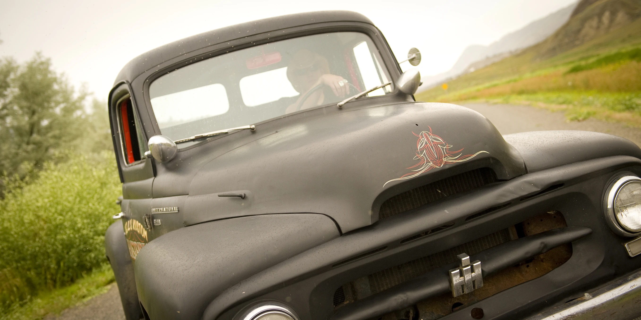 an old truck driving down a country road