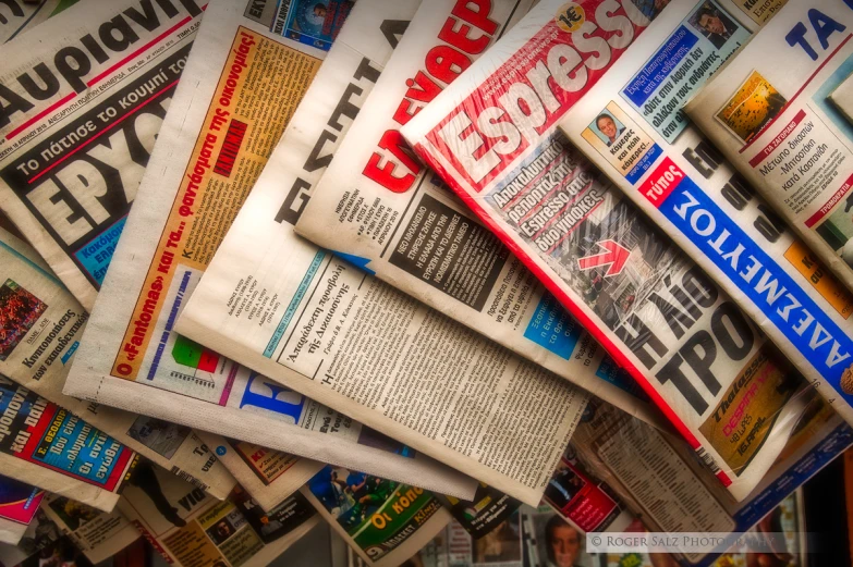 newspapers laying on top of each other with a person walking by them