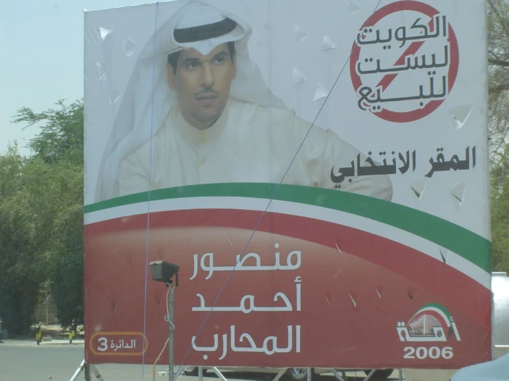a billboard advertises an arab president, on the side of a street
