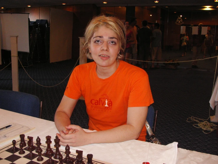 a woman sitting at a table with chess pieces