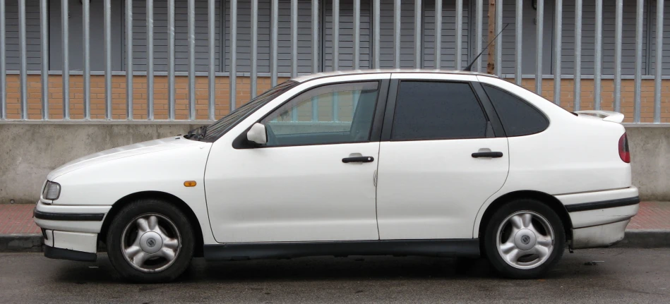 the car is white and parked near the wall