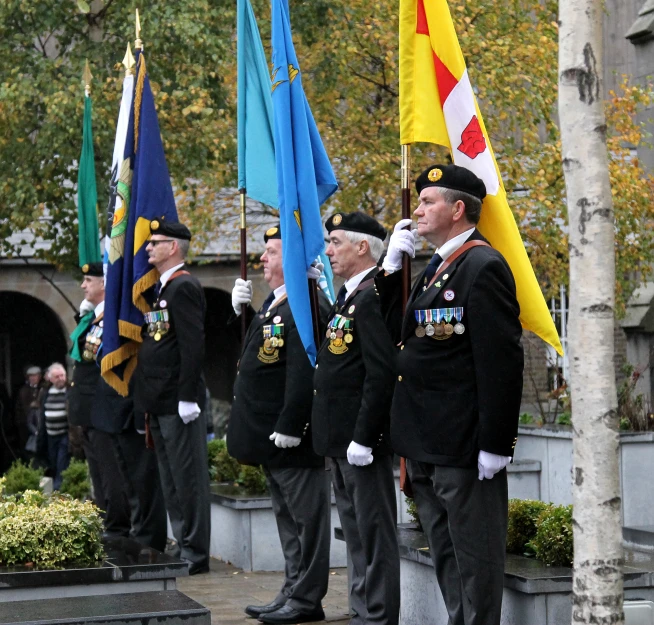 men in uniforms holding flags are standing by a group of trees