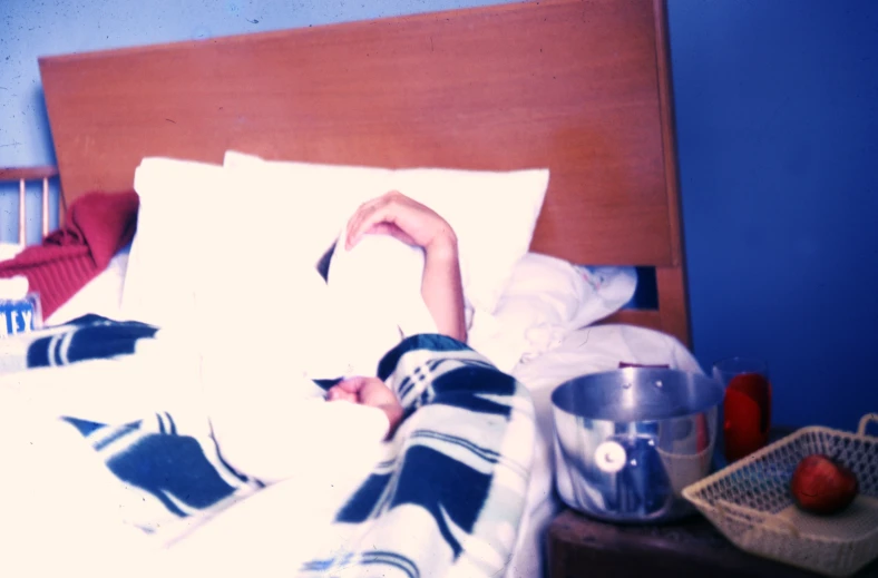 a young person laying in bed with blue walls