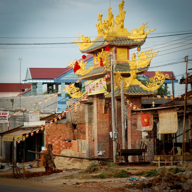 a big yellow statue above a small red brick building