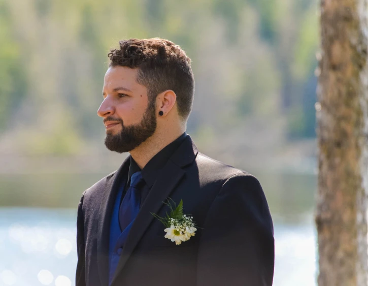 a man in a suit is standing near the water