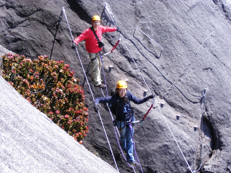 two men climbing up some steep rocks together