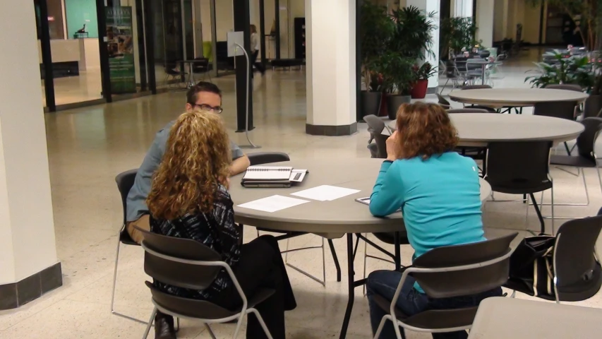 a couple of women sitting at a table and looking at a laptop computer