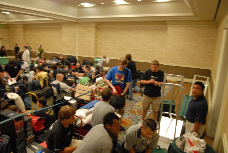 group of people gathered in an indoor terminal waiting for their luggage