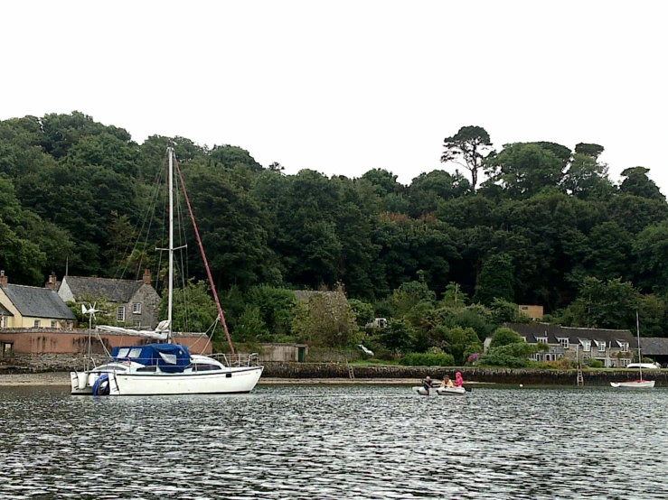 a sailboat floating on the ocean near small cottages