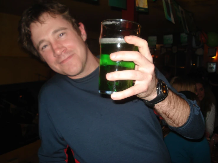 a man holds up his hand with green liquid in it