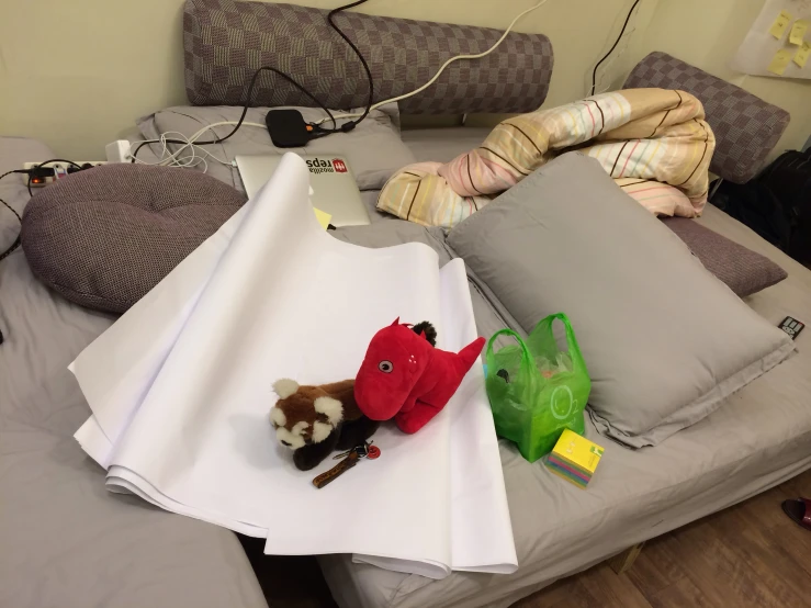 a bed with different types of pillows, a stuffed toy and a bag