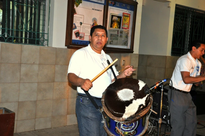 two men playing musical instruments in front of a large cow