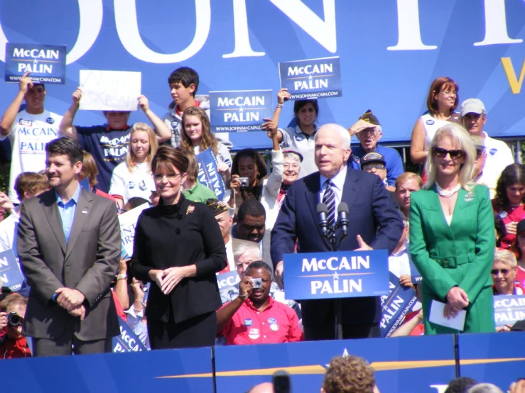 vice mccain, standing in front of supporters with signs and banners