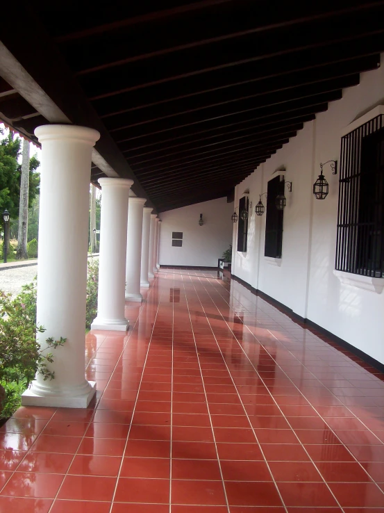 a red tile floor with white pillars and plants