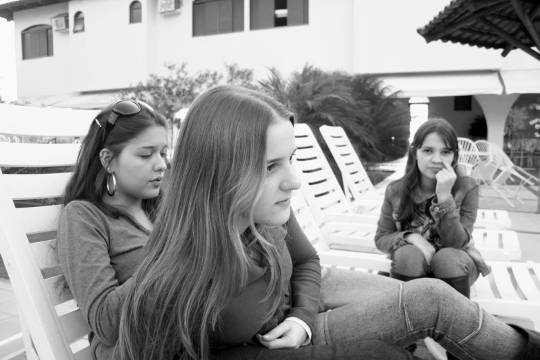 two girls sitting on some chairs looking away from the camera