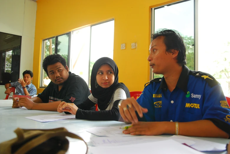 four young people sitting at a long table