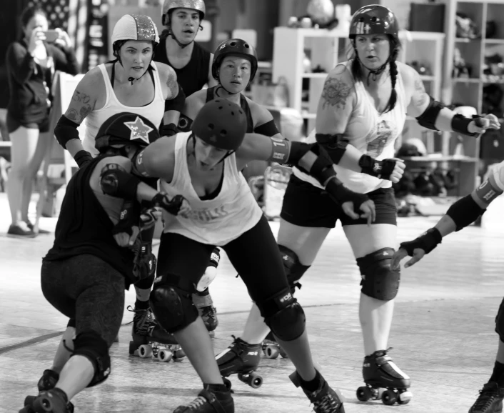 four women in roller skates on an indoor surface