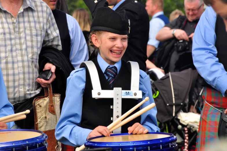 a boy in a school uniform playing on the drums